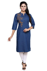 A woman modeling a blue denim-style kurta with gold floral embroidery on the chest, paired with white pants and black sandals, against a plain white background.