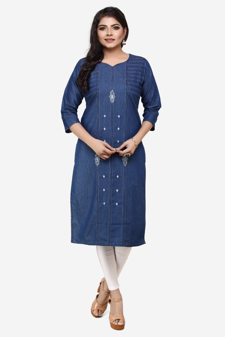 A woman modeling a blue denim-style kurta dress with decorative silver embellishments down the front, paired with white leggings and beige sandals, against a plain light gray background.