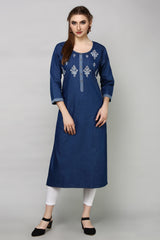 A woman modeling a dark blue cotton kurta with white embroidery on the chest and cuffs, paired with white leggings and black shoes, against a plain gray studio background.