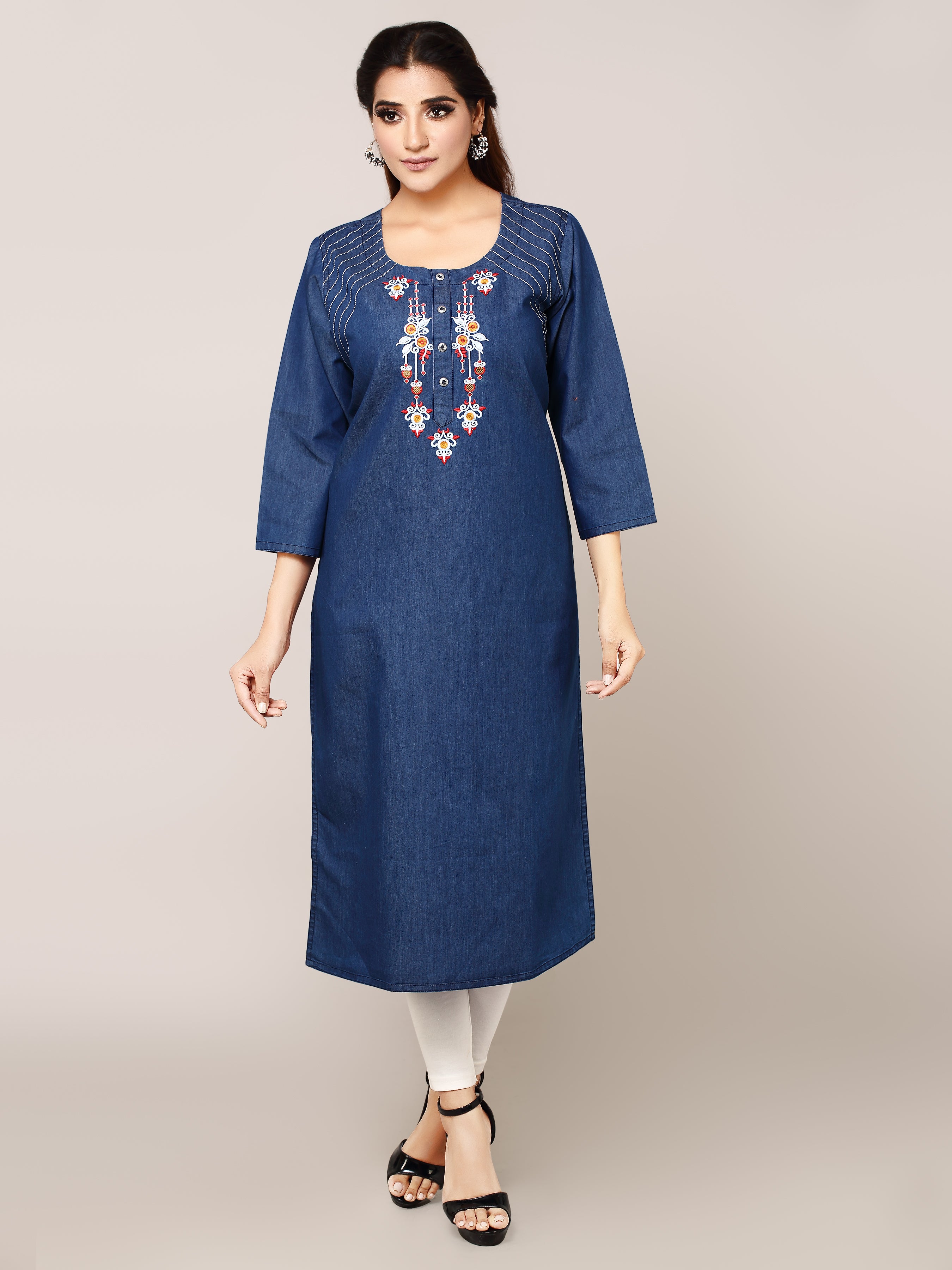 A woman modeling a blue three-quarter sleeve kurta with white and red embroidered details on the chest, paired with white leggings and black sandals, against a solid light gray background.