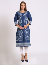 A woman modeling a navy blue cotton kurta with intricate white floral embroidery, paired with white leggings and navy blue heels, against a plain light gray background.