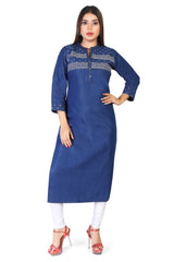 A woman modeling a blue denim-style long kurta with white printed geometric patterns across the chest and cuffs, paired with white pants and red high-heeled sandals, against a plain white background.