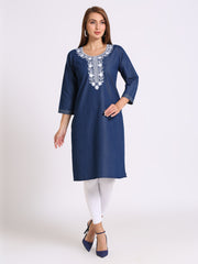A woman modeling a navy blue kurta with white embroidery around the neckline, paired with white leggings and navy blue heels, against a light gray studio background.