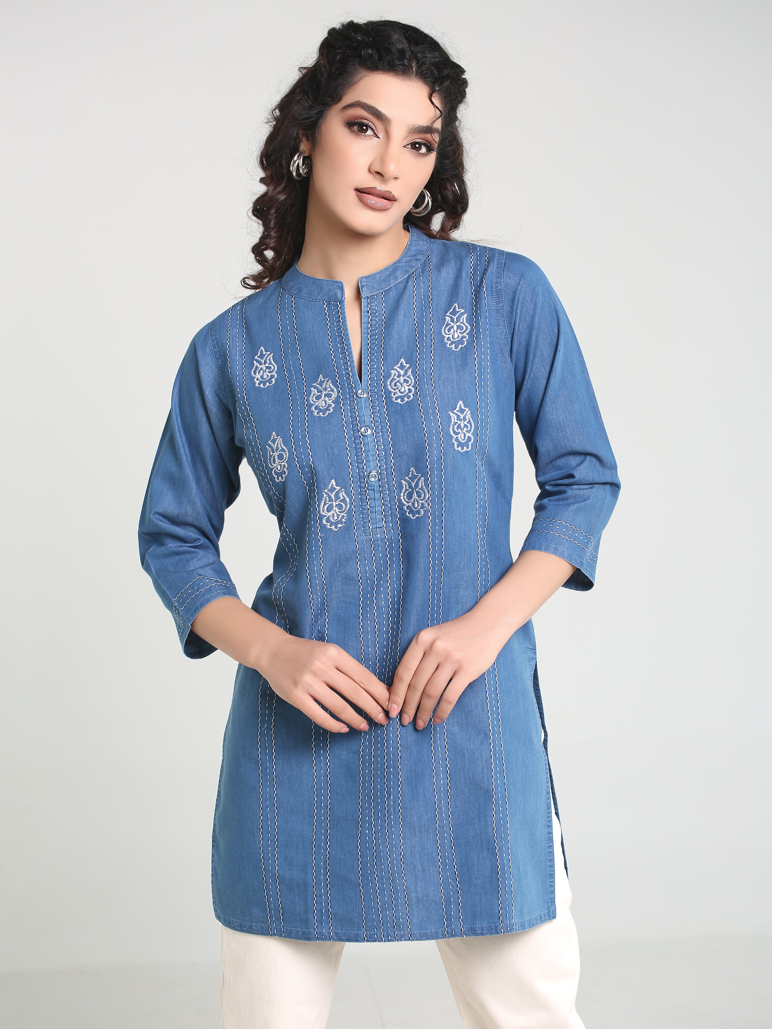 Woman wearing a blue embroidered kurta against a white background
